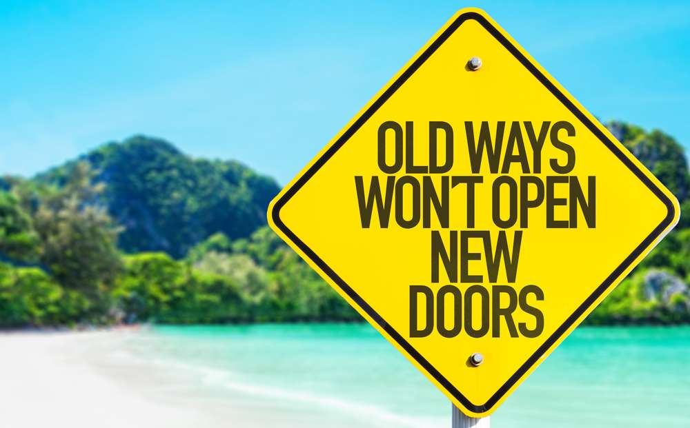 Old Ways Wont Open New Doors sign with beach background Old Ways Wont Open New Doors sign with beach background