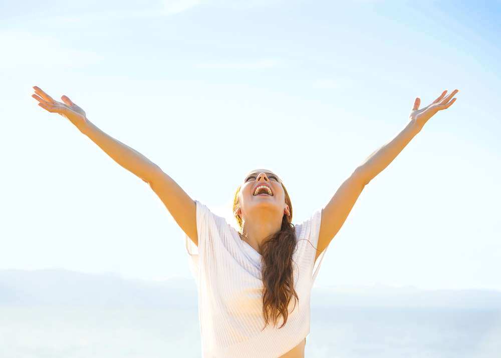 Woman smiling arms raised up to blue sky, celebrating freedom. Positive human emotions, face expression feeling life perception success, peace of mind concept. Free Happy girl on beach enjoying nature